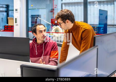 Two male technicians using computer in a cnc modern factory office Stock Photo