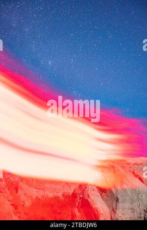 Arms reaching and waving in red light taken with a starry desert landscape in the background. Stock Photo