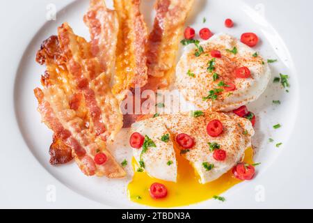 Portion of chili poached eggs with crispy bacon Stock Photo