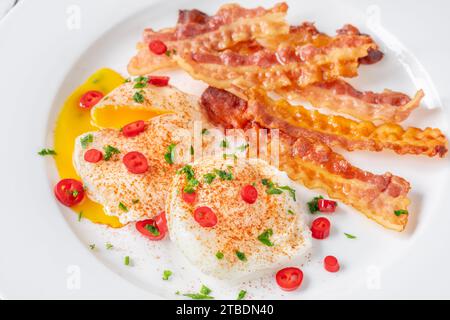 Portion of chili poached eggs with crispy bacon Stock Photo