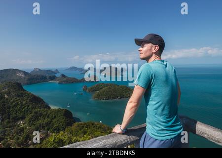 Happy man is enjoying amazing view from top of hill. Group of tropical islands in sea near Koh Samui in Thailand. Stock Photo