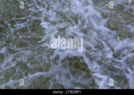Close up detail of fierce white water river rapids from a clean deep green colored river forming a textured background. Stock Photo
