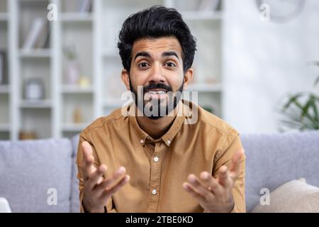 Hindu businessman having a video call in the home office gesturing a lot, student answering online lectures, view from webcam. Stock Photo
