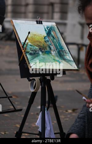 This image showcases a creative artist painting on an easel with a joyful expression on their face Stock Photo