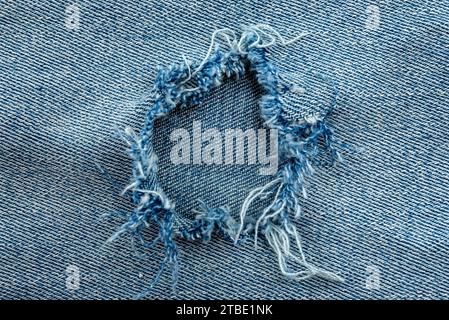 Hole in denim fabric. Ripped jeans Stock Photo