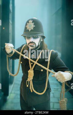 A portrait of a male cosplayer at a comic con event in a scary British Police uniform with white painted face and hangmans noose in old London town  i Stock Photo