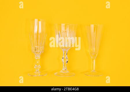 Three vintage crystal glasses on a yellow background. Minimal concept. Stock Photo