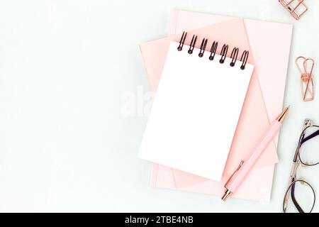 Workspace with empty notepad mockup and pink colored stationery on a blue background. Office supplies. Stock Photo