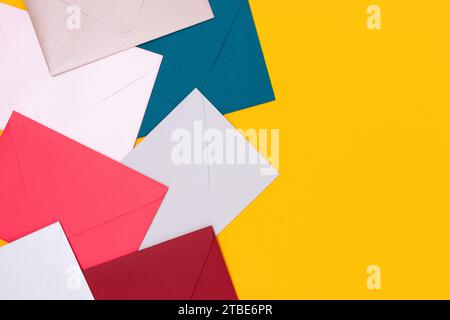 Multicolored envelopes scattered on a yellow background. Creative concept with place for text. Stock Photo