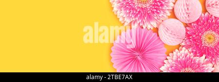 Banner with gerbera flowers, tissue paper fans and balls on a yellow background. Stock Photo