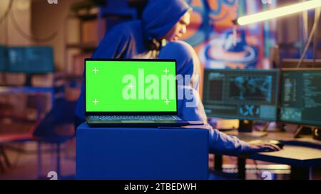 Green screen laptop in bunker with graffiti walls left behind by hackers to act as decoy. Mockup device running script pinging wrong location to cybercriminal law enforcement chasing them Stock Photo