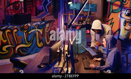 Hacker group coordinating DDoS attack on website, sending large amounts of traffic from multiple sources to overwhelm it. Rogue programmers working together to flood target server, slowing it down Stock Photo