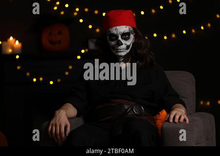 Man in scary pirate costume with skull makeup against blurred lights indoors. Halloween celebration Stock Photo