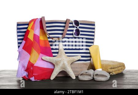 Stylish bag, starfish and other beach accessories on wooden table against white background Stock Photo