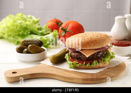 Tasty hamburger with patty, cheese and vegetables served on table Stock Photo