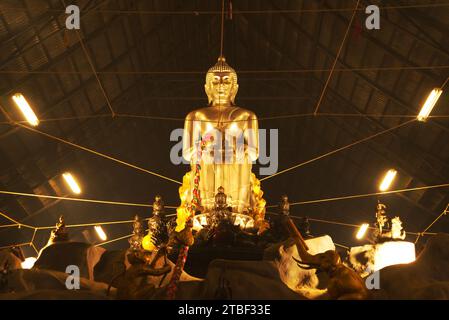 A large silver seated Buddha statue in the Pa Lelai pose. Inside the sermon hall At the bottom, devotees can walk under it. At Wat Tha Mai temple. Stock Photo