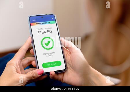 Online transaction complete. Woman holding a mobile phone with a financial application on screen.A person who transfers money online using application Stock Photo