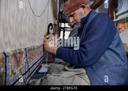 A Kashmiri artisan weaves a traditional carpet at a factory in Srinagar, the summer capital of Jammu and Kashmir. Famed the world over for their resplendent colour and intricate patterns, the carpets woven by the artisans of Jammu & Kashmir hold a centuries old legacy in their weave. The magnificent craft of carpet weaving was brought to the Kashmir valley from Persia in the 14th century. Kashmiri carpets are popular throughout the world for their quality material and authenticity and are specifically known for being handmade and unique in their exquisite style. The continued demand for carpe Stock Photo