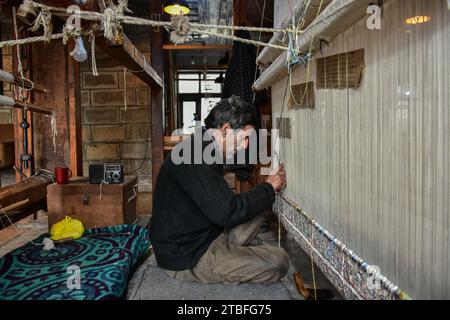 A Kashmiri artisan weaves a traditional carpet at a factory in Srinagar, the summer capital of Jammu and Kashmir. Famed the world over for their resplendent colour and intricate patterns, the carpets woven by the artisans of Jammu & Kashmir hold a centuries old legacy in their weave. The magnificent craft of carpet weaving was brought to the Kashmir valley from Persia in the 14th century. Kashmiri carpets are popular throughout the world for their quality material and authenticity and are specifically known for being handmade and unique in their exquisite style. The continued demand for carpe Stock Photo