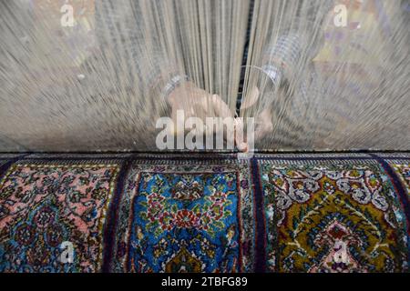 A Kashmiri artisan weaves a traditional carpet at a factory in Srinagar, the summer capital of Jammu and Kashmir. Famed the world over for their resplendent colour and intricate patterns, the carpets woven by the artisans of Jammu & Kashmir hold a centuries old legacy in their weave. The magnificent craft of carpet weaving was brought to the Kashmir valley from Persia in the 14th century. Kashmiri carpets are popular throughout the world for their quality material and authenticity and are specifically known for being handmade and unique in their exquisite style. The continued demand for carpe Stock Photo