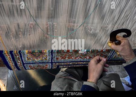 A Kashmiri artisan weaves a traditional carpet at a factory in Srinagar, the summer capital of Jammu and Kashmir. Famed the world over for their resplendent colour and intricate patterns, the carpets woven by the artisans of Jammu & Kashmir hold a centuries old legacy in their weave. The magnificent craft of carpet weaving was brought to the Kashmir valley from Persia in the 14th century. Kashmiri carpets are popular throughout the world for their quality material and authenticity and are specifically known for being handmade and unique in their exquisite style. The continued demand for carpe Stock Photo