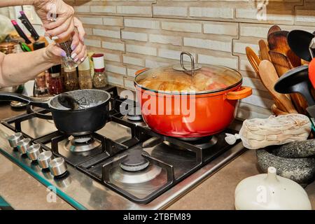 Close-up of cook's hands whisking beaten eggs and adding freshly ground pepper from a shaker, preparation for cooking delicious meal in the kitchen. Stock Photo