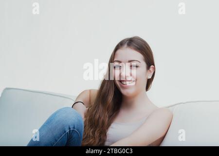 Comfortable in her own space, the young lady's casual pose and soft gaze suggest a peaceful ease Stock Photo