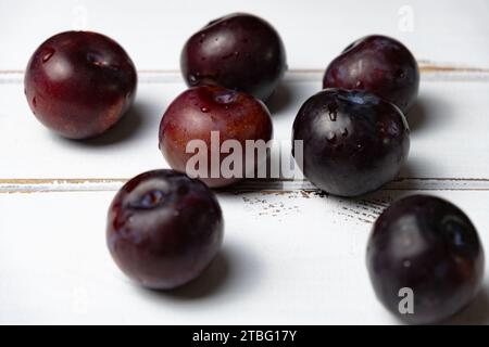 Red plums on a white wooden background, red plum concept idea photos. Stock Photo