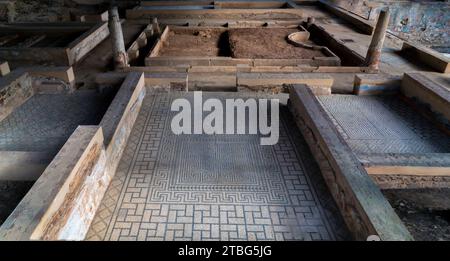 Remains of the archaeological ruins of a Roman mosaic on the floor of a room with blue geometric figures that create a fractal structure in the Mitreo Stock Photo
