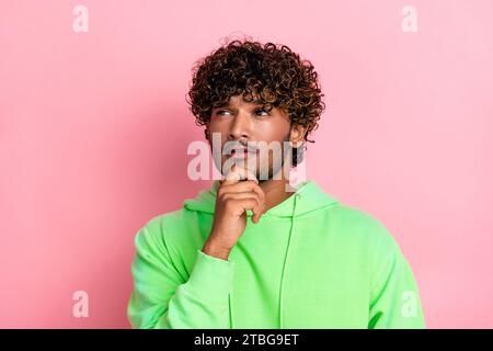 Portrait of indian young serious guy brainstorming touching chin pensive deep thinking look empty space isolated on pink color background Stock Photo