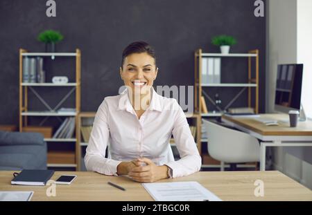 Headshot portrait of young confident smiling businesswoman smiling to camera Stock Photo