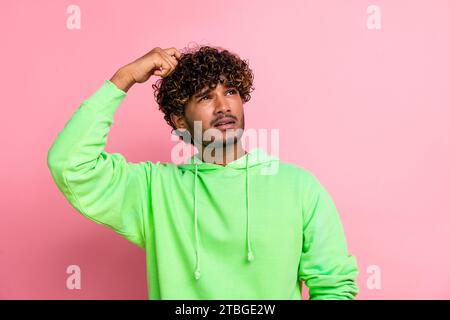 Portrait of thoughtful indian student wavy hair man scratch head looking empty space lectures schedule isolated on pink color background Stock Photo