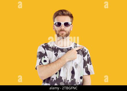 Cheerful man pin sunglasses pointing to side with forefinger Stock Photo
