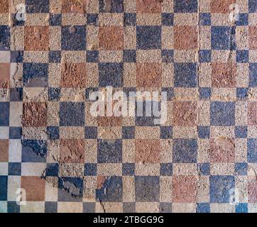 Archaeological remains of Roman mosaic with geometric figures, red and blue squares forming a checkerboard pattern on the floor of the Roman House Mit Stock Photo