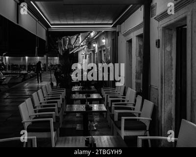 Cres, Croatia - October 23, 2022: An empty restaurant in the port of Cres during night, black and white Stock Photo