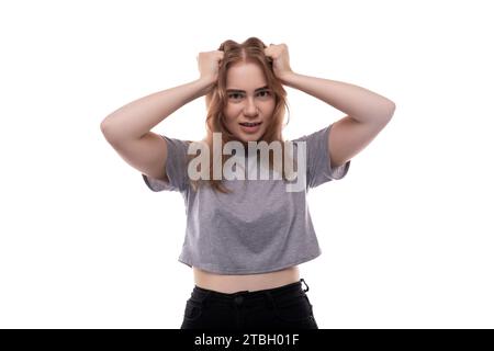 Teenage girl with blond hair in a gray T-shirt on a white background Stock Photo