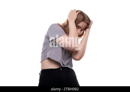 Fearful teenage girl with blond hair in a T-shirt on a white background Stock Photo