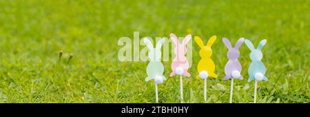 On a light blue background, Easter bunnies cut out of colored paper, scissors, felt-tip pens. Easter holiday concept, children's crafts, applique. Fla Stock Photo