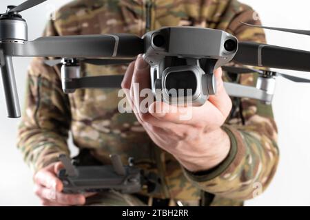Concept of using drones in modern warfare. Close-up of a drone in hands of a soldier on white background. Military use of drones Stock Photo