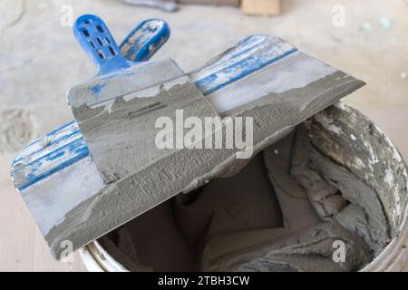 Spatula in a bucket with tile glue, facing tile mounting works Stock Photo