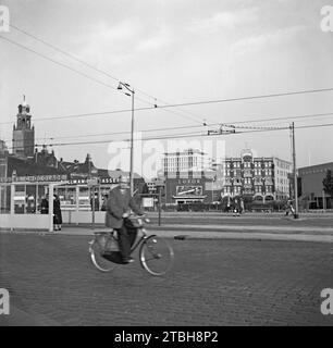 A view of Rotterdam in 1955 – this was photographed looking south from the tramstop on Weena as a cyclist rode by. In the distance is the Old Luxor theatre on Kruiskade – showing was ‘Vrouwen op Avontuur’ with Georges Marchal and Maria Mauban. Next to it is the Hotel Centraal. On the left is Stadhuis Rotterdam and its distinctive clock tower. The modern building is Holbeinhuis. The view has now gone with modern high-rise buildings built along Weena – a vintage 1950s photograph. Stock Photo