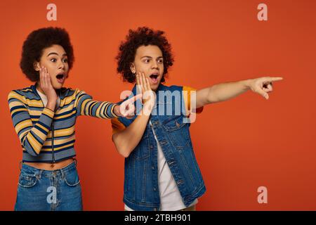 shocked african american siblings in casual attires pointing somewhere together, family concept Stock Photo