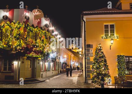 Beautiful cozy Christmas decorations, wreath, garlands and lights in Vilnius old town, capital of Lithuania, Europe, by night with street lamps Stock Photo