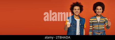 cheerful african american brother and sister gesturing actively and looking at camera, family Stock Photo
