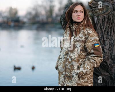 Ukrainian woman soldier resting in park during vacation near lake. Women and war in Ukraine. Russian military invasion. Translation from Ukrainian: Ar Stock Photo