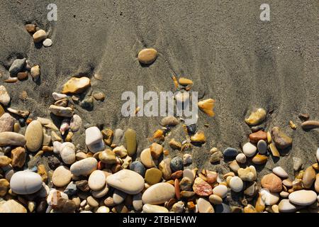 Beautiful background of colorful stones on a sandy wet beach. Sea pebbles, top view Stock Photo