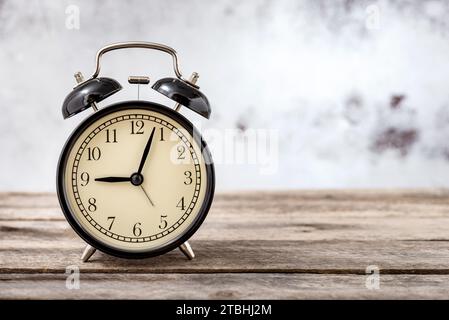 Vintage black alarm clock on rustic wooden table with copy space for text. Stock Photo