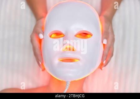 woman getting cosmetic procedure with LED anti-aging facial mask in beauty salon Stock Photo