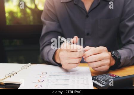 Businessman holding a pen with documents in home office. Stock Photo