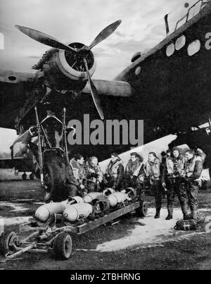 The flight crew of a Stirling heavy bomber watch their aircraft being 'bombed' up prior to a night raid on Berlin, Germany on the 7th September 1941 - the first annivery of the first bombing by the Luftwaffe on London during the Second World. Stock Photo